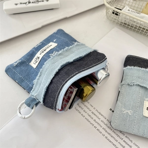 Macro view of blue denim patchwork coin purse with frayed edges and zipper closure