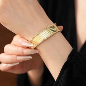 Détail d'un bracelet manchette doré strié avec des bords pavés de cristaux brillants