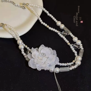 Détail d'un collier de perles rétro français avec une fleur en résine givrée translucide