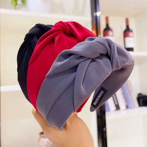 Detail of three wide twisted headbands in black, red, and grey with handmade label