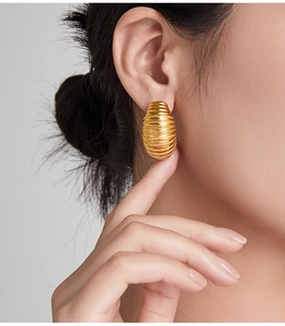 Macro shot of gold-plated geometric C-shaped earrings with spiral layered textures