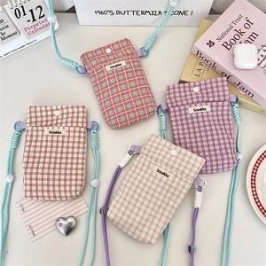 Detail of plaid crossbody phone bags featuring colorful woven drawstrings and fabric texture