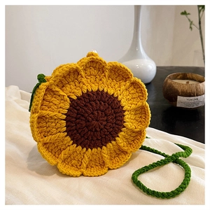 Detail of hand-woven sunflower crochet bag with green strap on soft white fabric