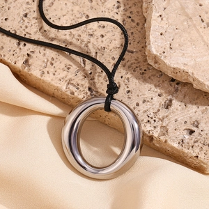 Detailed view of silver minimalist ring pendant with black cord on natural stone texture
