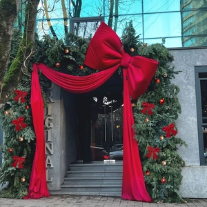 Giant red velvet bow decoration for storefront entrance with green pine and ornaments