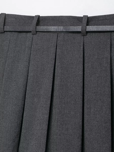 Detail of dark gray pleated culottes featuring textured fabric and a black leather belt