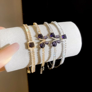 Détail de bracelets papillon en zircon et gemmes mauves sur rouleaux de velours