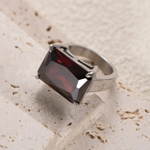 Close-up of a silver titanium ring with a large rectangular red gemstone on stone