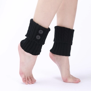 Detail of black cable-knit leg warmers featuring decorative side buttons and texture