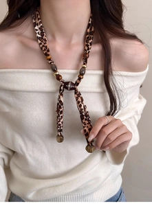 Detail of leopard print heart necklace with Vivienne Westwood logo and brown beads
