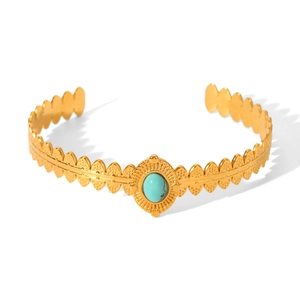 Detailed view of vintage gold hollow cuff bracelet with oval turquoise stone inlay