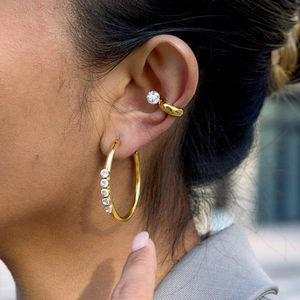 Detailed close-up of 18K gold stainless steel hoop earrings and ear cuff with zircons