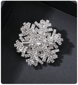 Macro shot of silver rotating snowflake brooch with inlaid crystals on black display box