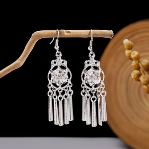 Detail shot of silver ethnic leaf tassel earrings hanging on natural wood background