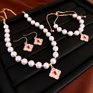 Luxurious gold-plated pearl jewelry set with red gemstone flower pendants in a tray