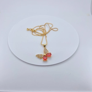 Detailed close-up of gold-plated butterfly pendant with red crystals and micro-inlaid zircons