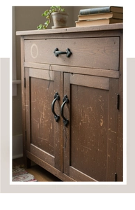 Close-up of vintage cast iron handles on a rustic dark wood cabinet with antique finish