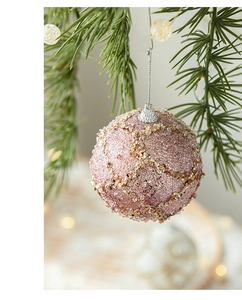 Detailed close-up of pink foam Christmas ball with gold sequins on green pine branches