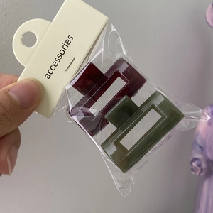 Detail of dark red and forest green hollow square hair clips in transparent retail packaging