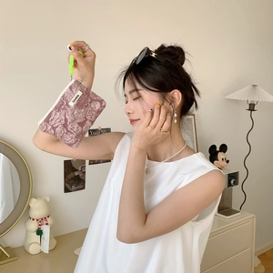 Detailed view of floral jacquard mini makeup pouch with green drawstring and brand label