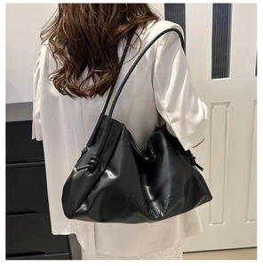 Detail showing the black large-capacity tote bag with knot decor on a model's shoulder
