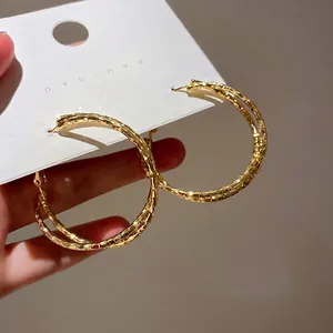 Golden double hoop earrings with textured finish shown on a jewelry display card