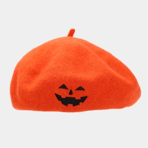 Detailed embroidery of a black pumpkin Jack-o'-lantern face on an orange wool beret