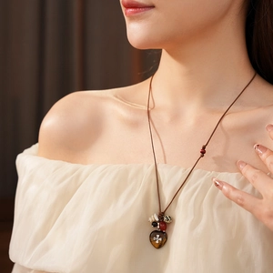 Detail of bohemian wax rope necklace with colorful wooden beads and heart-shaped pendant