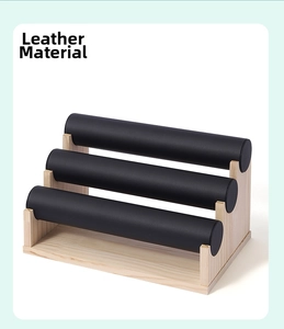 Three-tier jewelry display stand with black leather cylinders and natural wood base