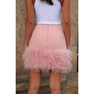 Détail d'une mini-jupe rose moulante avec bordure en plumes et fermeture éclair invisible