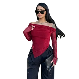 Detail of red off-shoulder top with sheer mesh sleeves and an asymmetrical hemline