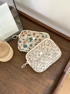Detailed view of quilted cotton pouches in beige and pink floral patterns on wood