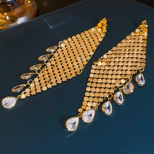 Macro shot of gold tassel earrings with mesh structure and cubic zirconia water droplets