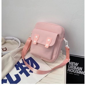 Detail view of pink canvas crossbody bag with white buckles and adjustable strap