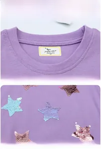 Detail eines lila Kleinkindkleides mit Rundhalsausschnitt und Pailletten-Sternstickerei