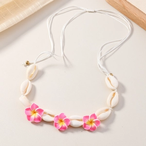 Gros plan d'un collier de coquillages avec fleurs de frangipanier sur cordon tressé