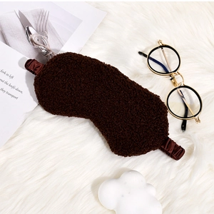 Detailed view of a soft brown plush sleep mask on a cozy white faux fur background