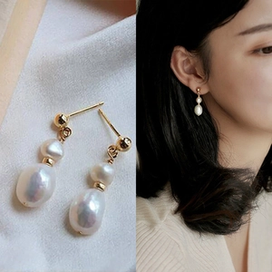 Detail view and model wearing golden double pearl drop earrings with natural teardrop shape
