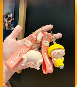 Close-up of cute pink pig keychains featuring a scooter and funny pose on hand
