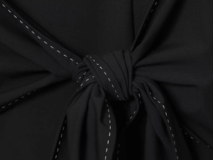 Close-up of knotted black fabric with decorative white dashed stitching details