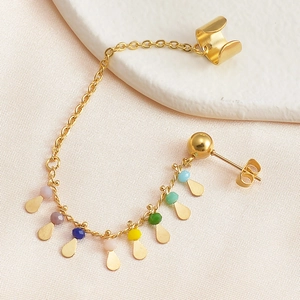 Detailed shot of golden ear cuff chain with colorful beads and waterdrop pendant