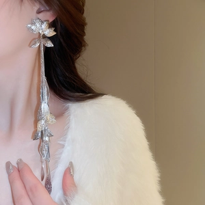 Gros plan de boucles d'oreilles fleurs et feuilles argentées montrant texture et drapé