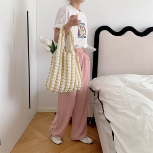 Detail of yellow and white striped bubble texture tote bag worn over the shoulder