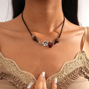 Detail of vintage tiger eye beads with strawberry and flower pendants on a woven necklace