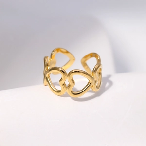 Macro detail of gold adjustable ring featuring a hollow heart design and polished finish