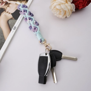 Close-up of handmade woven flower keychain with purple petals and gold lobster clasp