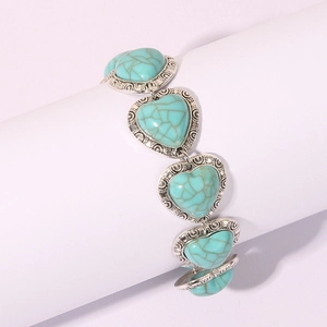 Vintage heart turquoise bracelet with silver engraved ethnic patterns on white stand