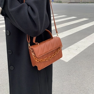 Sac bandoulière matelassé caramel avec chaîne décorative et bandoulière en cuir en vue rue