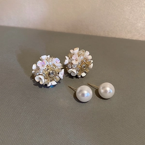 Gros plan détaillé de boucles d'oreilles fleurs vintage et perles sur fond texturé sombre