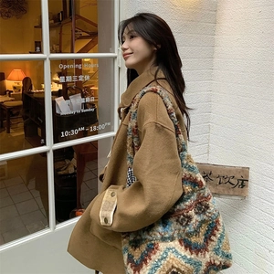 Detail of colorful geometric plush tote bag paired with a brown wool coat on the street